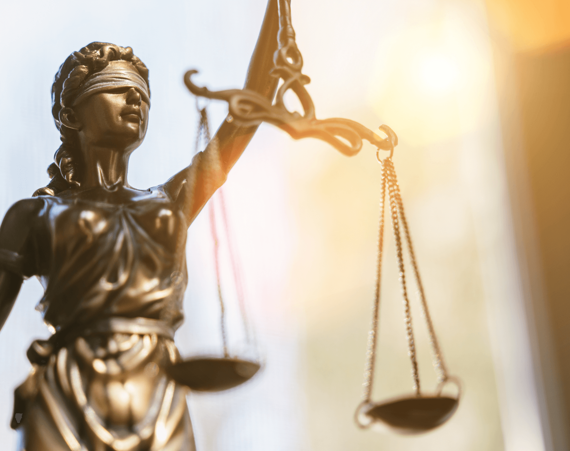 A golden figurine of 'Lady Justice', a blindfolded woman holding a set of scales who represents a moral force in judicial systems.